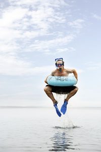 Man with kids swimming gear jumping in water